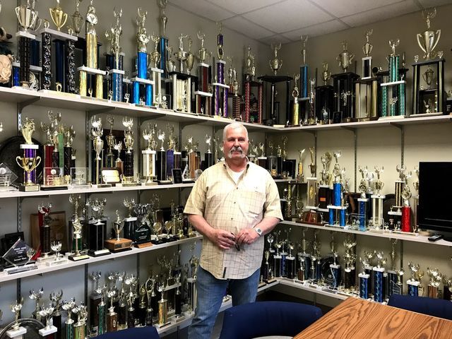 Director+Wayne+Kraemer+stands+among+trophies+from+past+speech+and+debate+tournaments.%0APhoto+by+StaceyRamirez+%7C+Lifestyle+Reporter