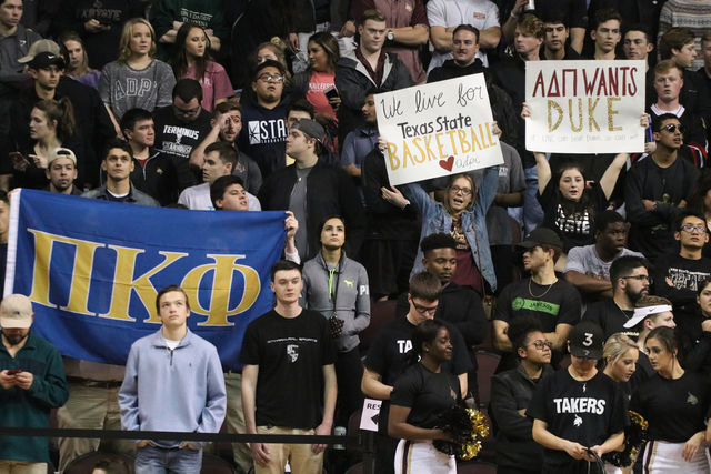 Greek students show their support at the basketball game with flags and signs.Photo by Kate Connors.
