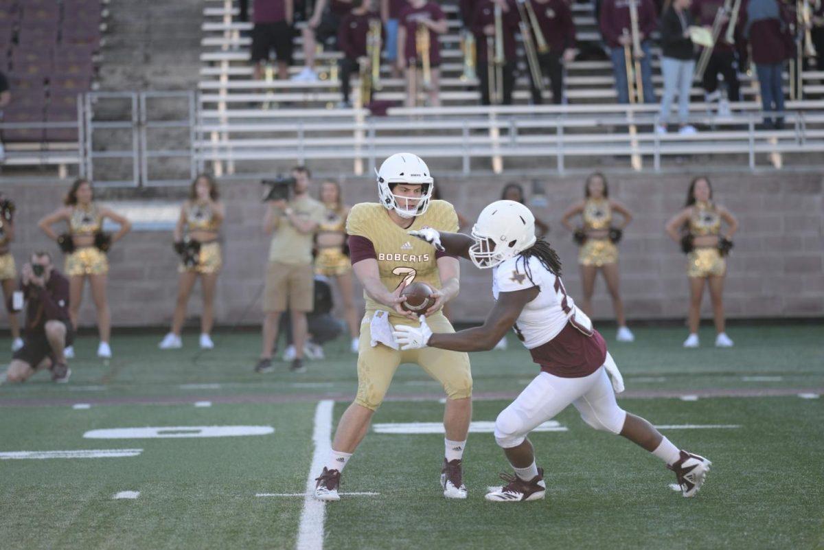 Junior transfer quarterback Gresch Jensen handing off the ball April 13 to senior running back Anthony D. Taylor. Courtesy image by Texas State Athletics.