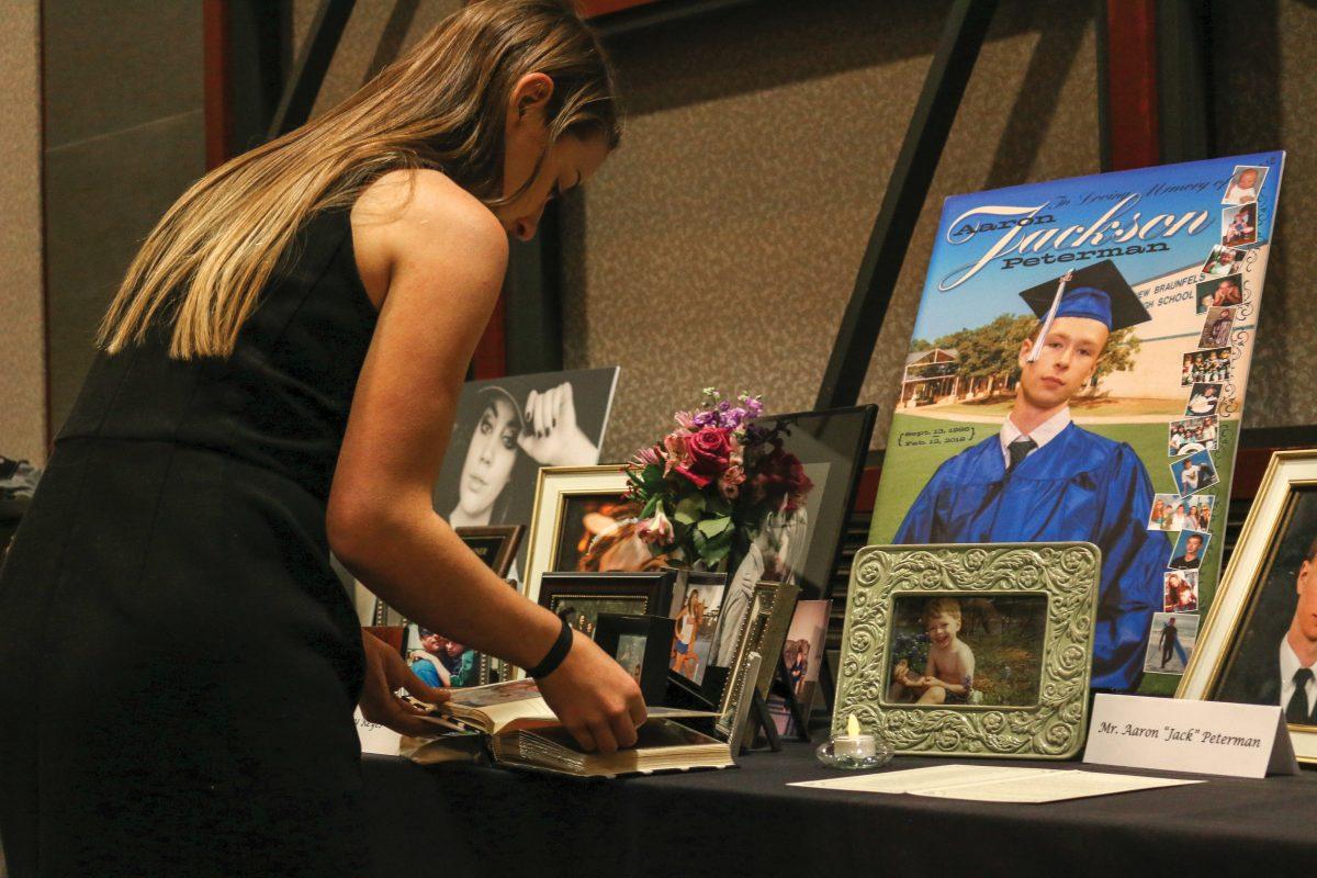 A student visits Mr. Aaron “Jack” Peterman’s tabled memorial and looks through photos April 11 at the Bobcat Pause Memorial Service in the LBJ Ballroom.