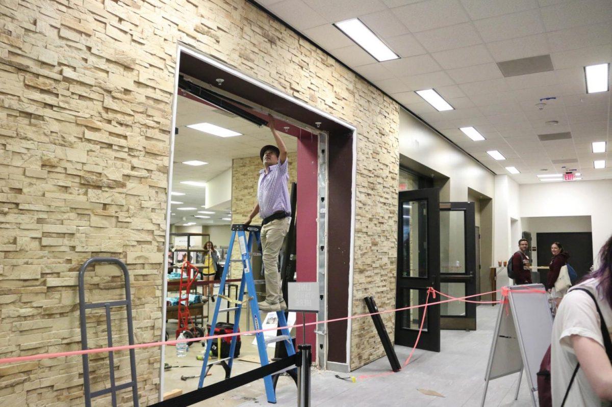 Abel Rodriguez of San Marcos Glass works to remove the remaining pieces of an old door frame June 24 at the bookstore located in the LBJ Student Center. Photo credit: Jaden Edison