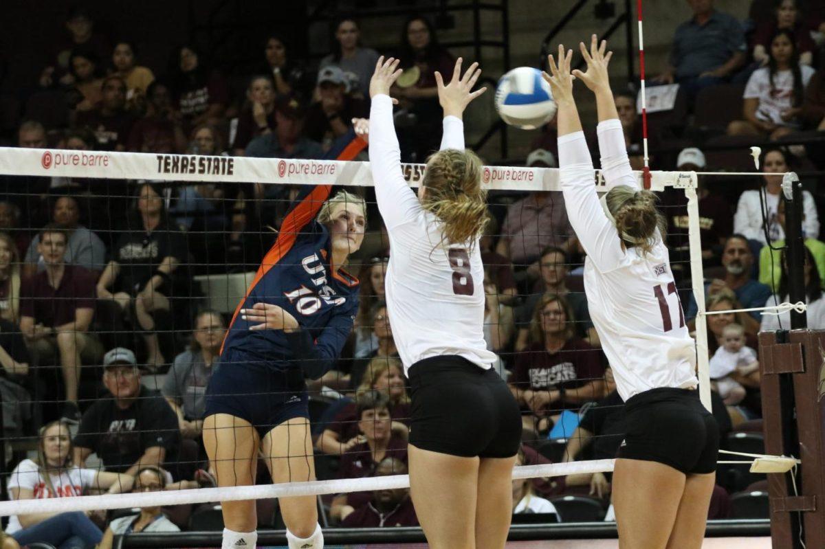 Sophomores Jill Slaughter (8) and Emily DeWalt (17) jump in an attempt to double block a UTSA player’s hit across the net during the Sept. 19 game at Strahan Coliseum. Photo credit: Kate Connors