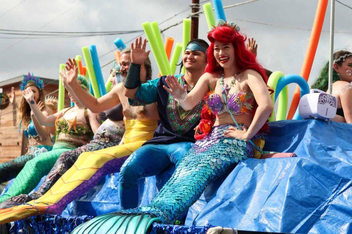 Workers of the Adventure Mermaid swim school wave to a crowd, Saturday, Sept. 21, 2019, during the Mermaid Promenade in downtown San Marcos. [Photo by Kate Connors]