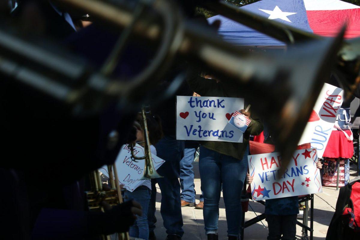 Attendees of the San Marcos Veterans Day Parade hold and display their signs as veterans, the San Marcos High School Band and others pass by, Saturday, Nov. 9, 2019, in downtown San Marcos. [Photo by Jaden Edison]