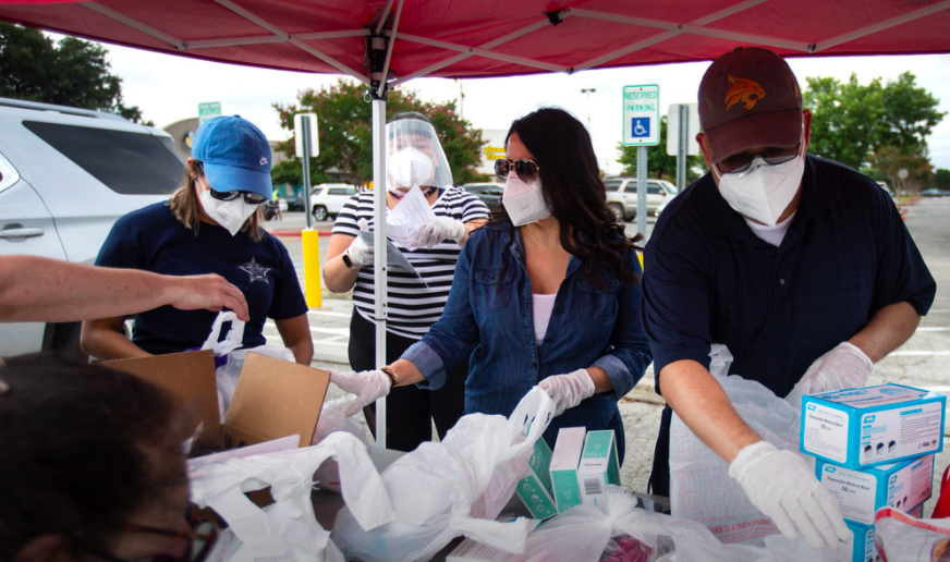 Diana Anzaldua (left) and Jason Rubio (right) help distribute 8,000 masks and personal protective equipment (PPE) kits for those in need in front of Wayside School in South Austin.
