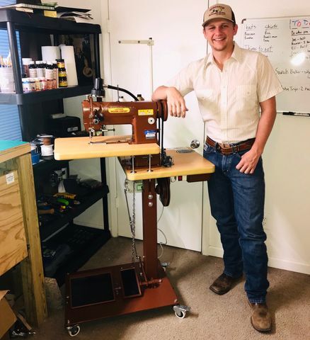 Self-taught leather crafter Trevor Weinaug, a business marketing senior, stands next to a Cobra Class 26 sewing machine inside his workspace. (Photo courtesy Trevor Weinaug)