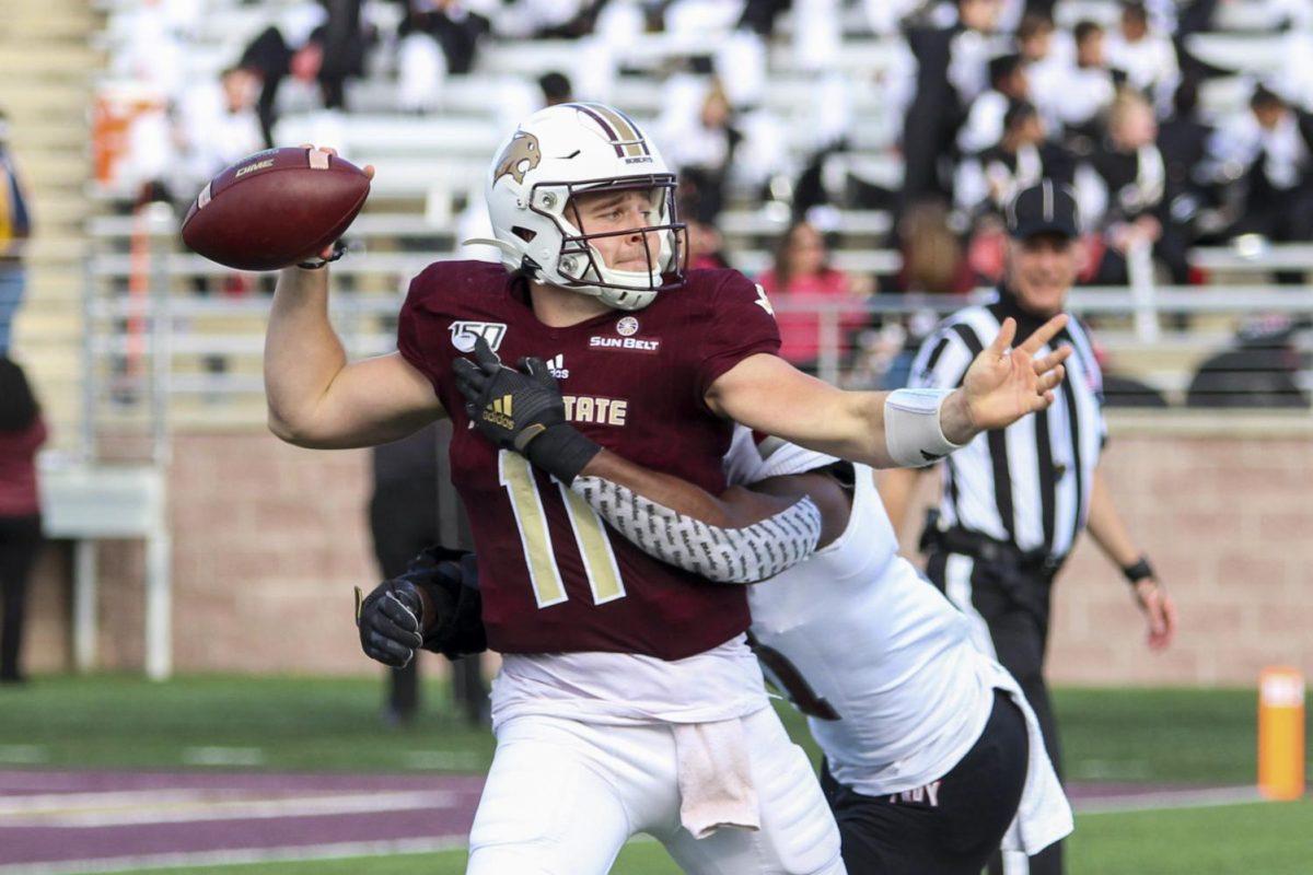Quarterback Tyler Vitt attempts to throw a football while being hit by a defender at a Texas State football game vs. Troy, Saturday, Nov. 16, 2019, at Bobcat Stadium.