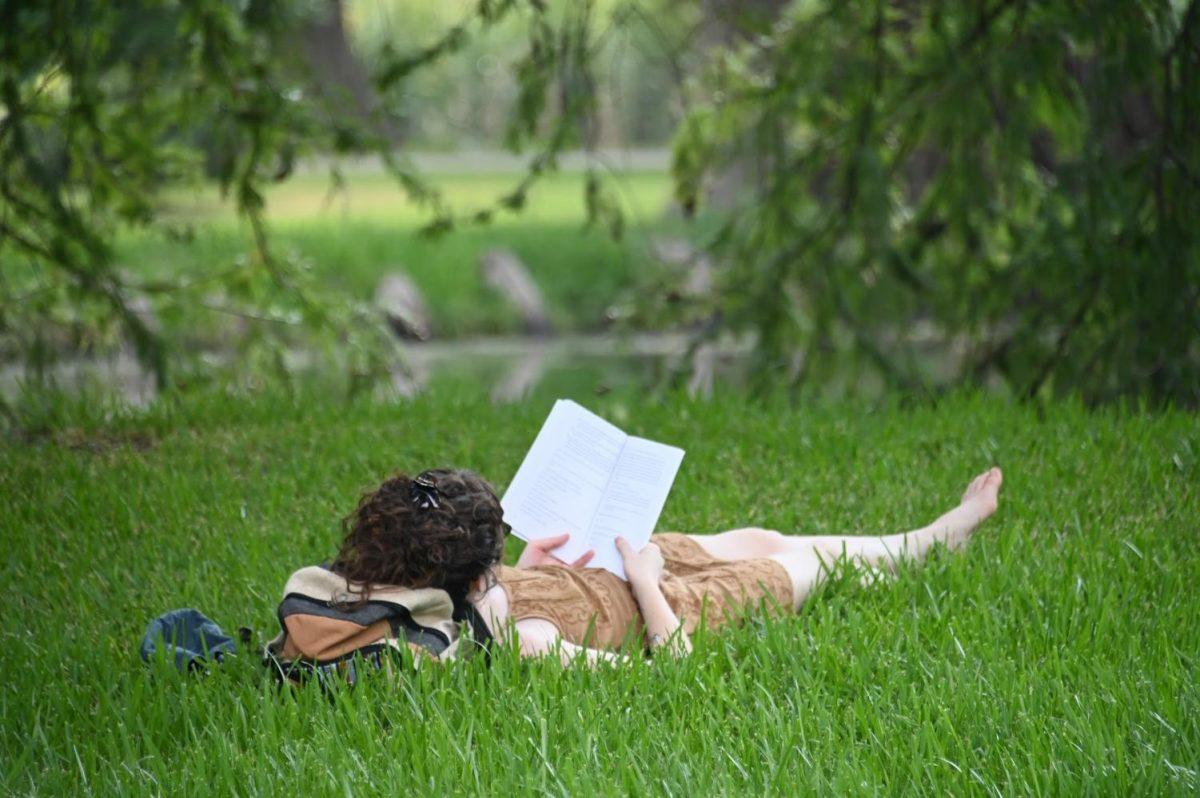 Theater major Leah Ingram reads a book in a grass field, Monday, Aug. 31, 2020, near the Texas State Theater Center.
