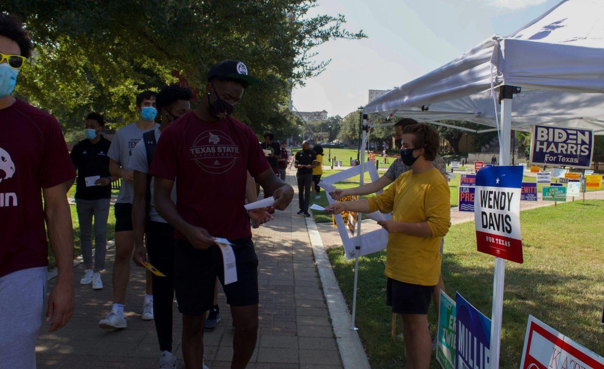 Members of the Texas State Democrats hand out fliers to the mens basketball team before they vote Oct. 13, 2020 at the Texas State Performing Arts Center. The PAC saw 1,125 ballots and 29 provisional ballots cast in the first two days of early voting.