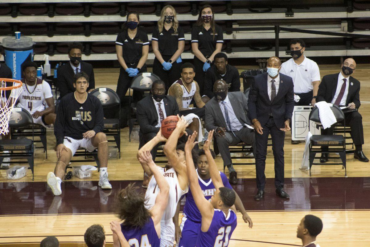 Texas State senior forward Quentin Scott (14) shoots a contested jump shot surrounded by University of Mary Hardin-Baylor defenders as the bench looks on, Wednesday, Nov. 25, 2020, at Strahan Arena. The Bobcats won 98-59.