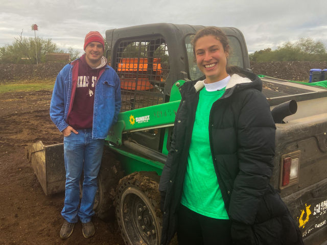 Taylor Levy with the Hays County Food Bank and Jack Traugott with Bobcat Blend smile in front of the Bobcat rental from Sunbelt that helped load up compost for the food banks new planter box.
