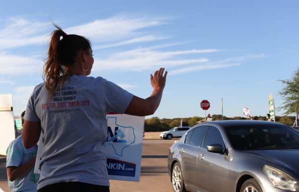 Emma Junkin, daughter of Judge David Junkin, waves to cars as they enter the Hays County Government Center, Tuesday, Nov. 3, 2020, in San Marcos. 