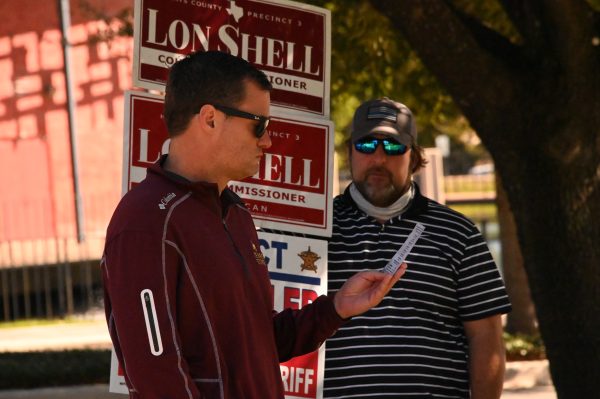 Jordan Berry (left) reads a voting information leaflet as Will Conley (right) looks on, Tuesday, Nov. 3,  2020, at the Performing Arts Center on Texas State's campus. Conley was campaigning to reelect Hays County Sheriff Gary Cutler and Commissioner Lon Shell.