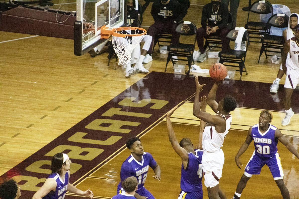Texas State junior forward Alonzo Sule (25) shoots a hook shot over a University of Mary Hardin-Baylor defender, Wednesday, Nov. 25, 2020, at Strahan Arena. The Bobcats won 98-59.