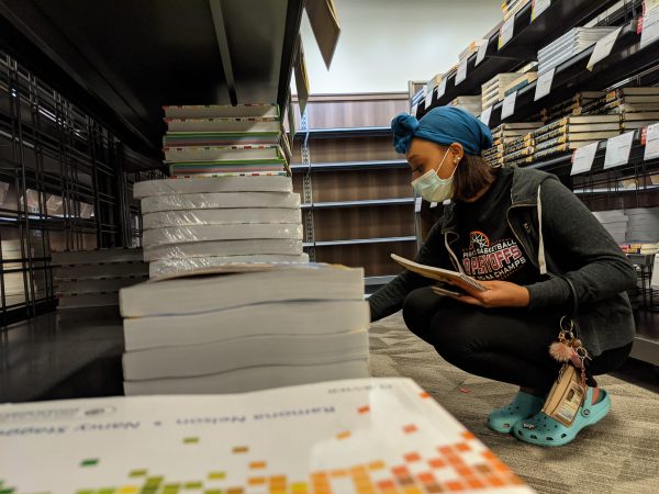 Biology freshman Ayanna Greene searches for a textbook for her new biology lab class, Tuesday, Jan. 19, 2021, at The Bobcat Store.  The university community returned to campus for the first day of the spring semester.