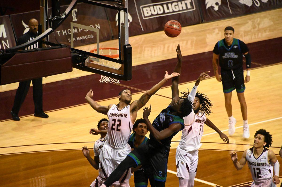 Texas State and Texas A&M Corpus Christi players reach out to grab the ball by the hoop, Tuesday, Dec. 15, 2020, at Strahan Arena. Texas State won the game 51 - 46.