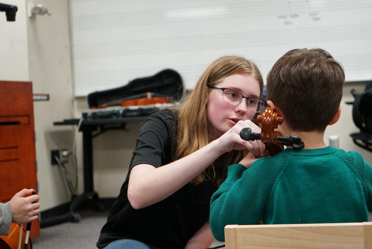 Music major Rachel Watson works with a beginning cello student on instrument position and bow hold in 2019.