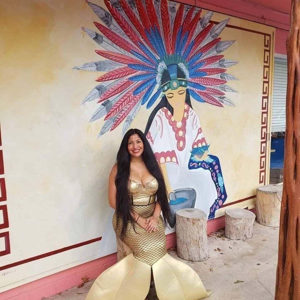 Jessica+Mej%26%23237%3Ba%2C+pictured+in+her+Sirena+del+Rio+costume%2C+sits+by+a+mural+of+an+Indigenous+woman.