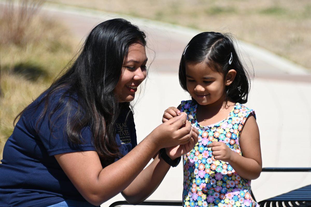 (Left to right) Texas State meteor science engineering doctoral student Fatema Zohra and her daughter, Maya, blow on a dandelion, Sunday, March 7, 2021, at Ingram Hall.