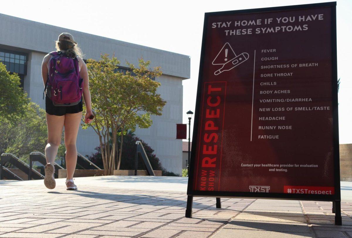 A sign alerting students to stay home if they are experiencing any symptoms of sickness is posted, Monday, Aug. 24, 2020, outside of the LBJ Student Center. 