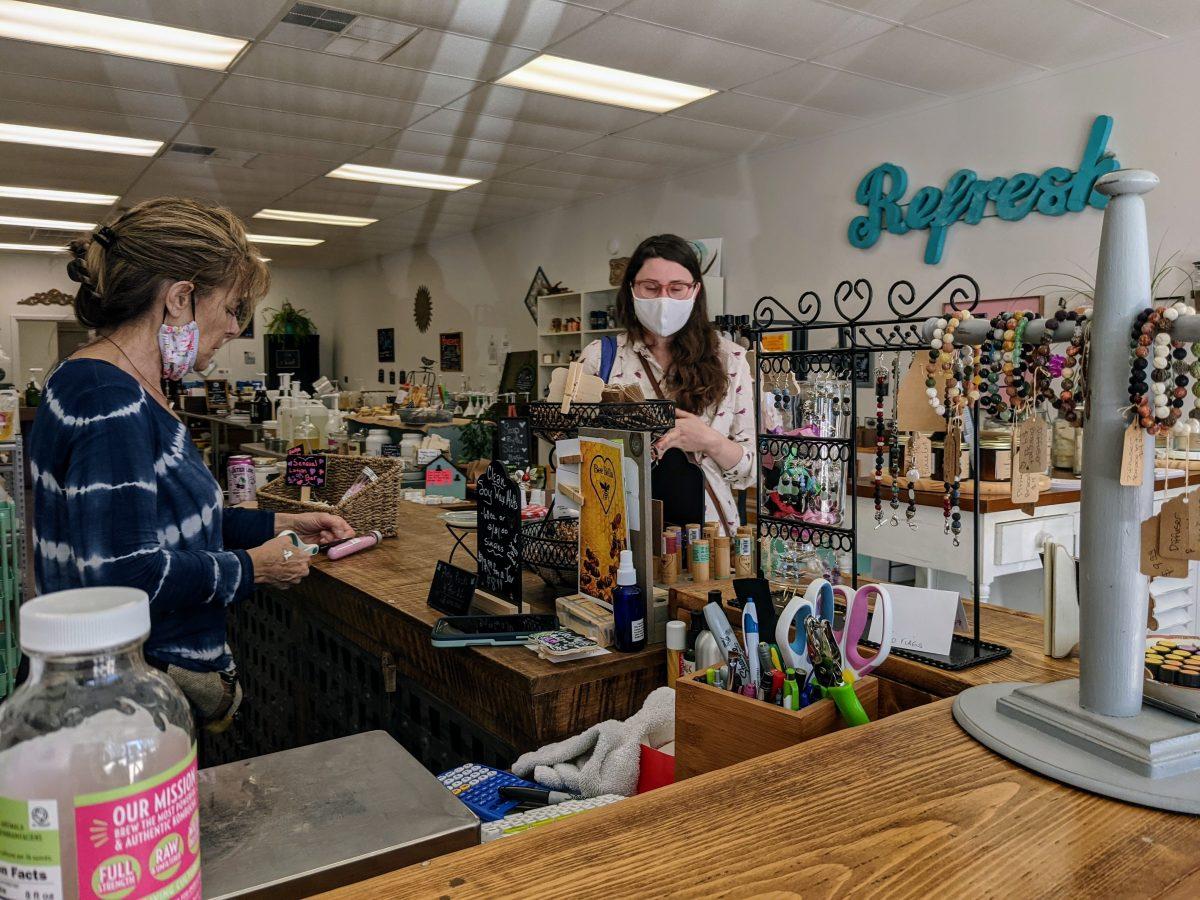 Manor Market Refillery co-owner Holly McGarvey (left) labels a small bottle while talking to customer Kali Page, Wednesday, March 3, 2021, at Manor Market Refillery.