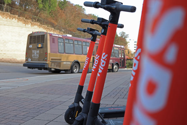 Electric scooters stand along the walkway, Tuesday, March 23, 2021, at the Quad Bus Loop