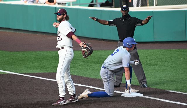 Georgia State freshman outfielder Kyle Riesselmann (3) kneels on first plate as umpire Chris Booker declares him safe and Texas State senior infielder Cole Coffey (25) readies a throw toward the mound, Friday, May 14, 2021, at Bobcat Ballpark. The Bobcats lost 4-7.