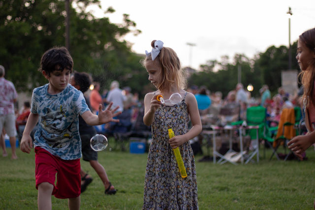 Kids play with bubbles while others watch the concert, Thursday, June 10, 2021, at San Marcos Plaza Park.