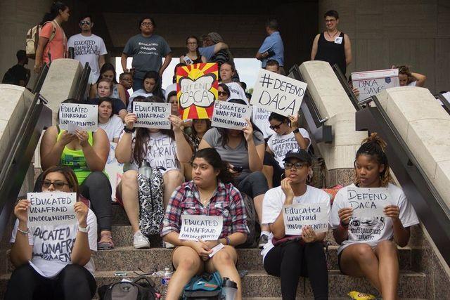 A group of students sit on the steps of Alkek Library and hold up signs with slogans such as, #Defend DACA and Educated Unafraid Undocumented. The Attorney for Students (AFS) Office is located at LBJ Student Center 5-1.5.