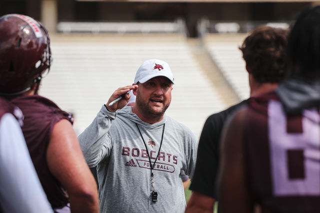 Head coach Jake Spavital talks to the offense at the conclusion of the first practice of fall camp, Friday, Aug. 6, 2021, at Bobcat Stadium.