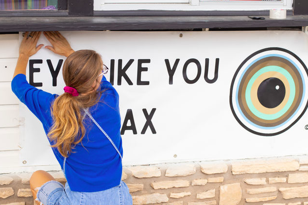Eye Like You co-owner Whitney Anderson hangs up a business sign, Monday, August 30, 2021, at Red Bus Food Park.
