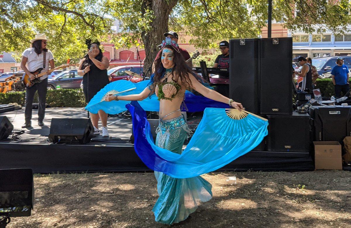A woman in a mermaid themed costume dances with her silk fan veils at the Fifth Annual Mermaid Promenade & Downtown Street Faire, Saturday, Sept. 25, 2021, outside the Hays County Historic Courthouse.