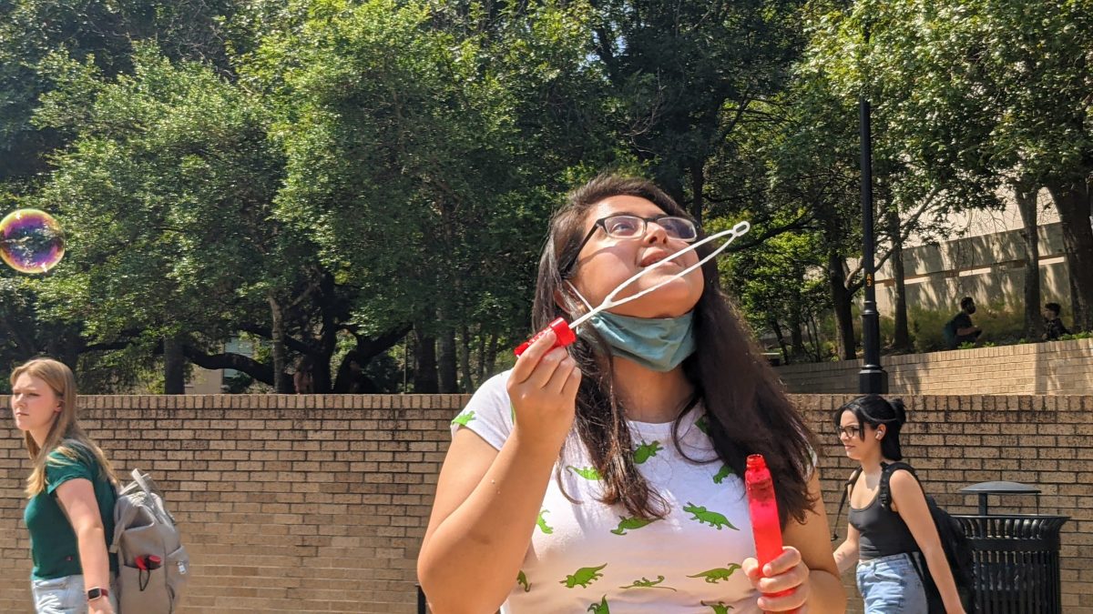 Texas State wildlife biology junior Shannon Cerda beams with delight while looking at the bubbles she blew, Wednesday, Sept. 1, 2021, at the courtyard near Evans Liberal Arts building and Derrick Hall. Cerda was one of the few students who were also blowing bubbles with the wands provided by the Bubble Believer. She believes that blowing bubbles is a stress reliever during busy week days.