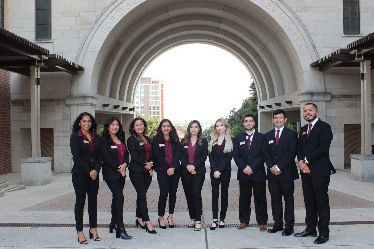 The Hispanic Business Student Association 2021-2022 executive council smile for a photo underneath the arch.