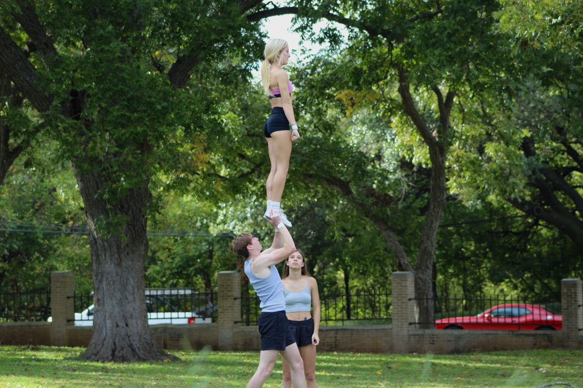 Texas State freshman cheerleaders Garrett Simmons and Hadley Brooks practice a lift while freshman cheerleader Gabrielle Geer observes, Wednesday, Nov. 10, 2021, at Sewell Park.