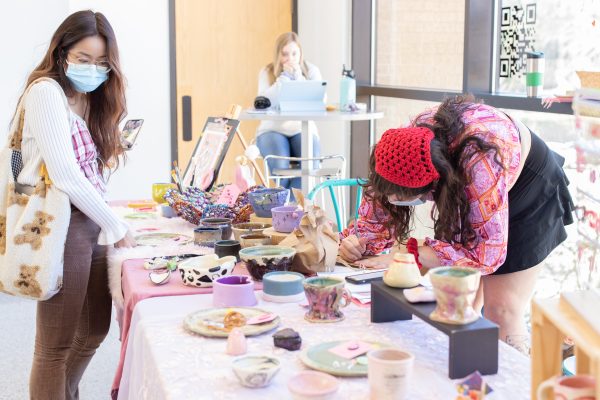 Texas State studio art senior Mikayla McDonough (right) packages a purchased item at the Valentine's Day Sale by the Ceramic Arts Student Association, Monday, Feb. 14, 2022, at the Joann-Cole Mitte Building. CASA is a student group of artists interested in ceramics.
