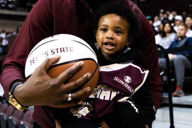 Texas State basketball senior Shelby Adams (4) son, Jace, wears Adams old uniform in support during the white out game against Arkansas State, Thursday, Feb. 17, 2022, at Strahan Arena.