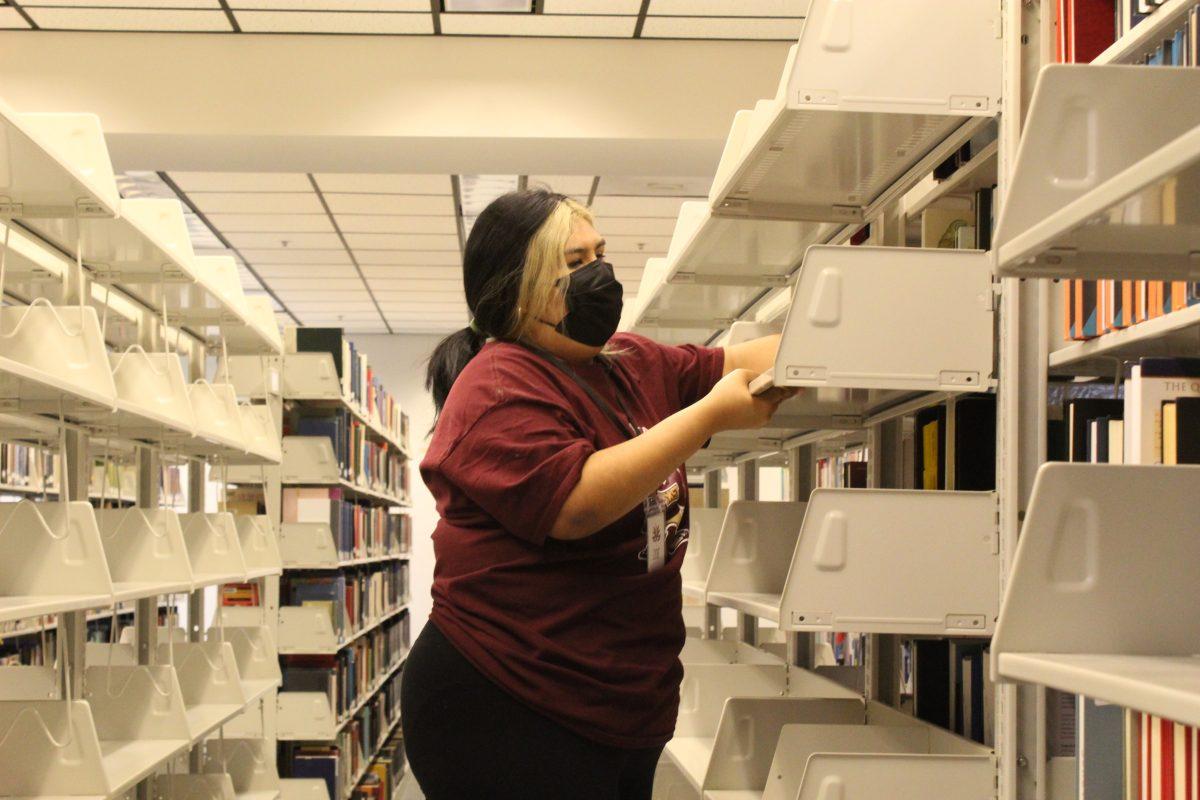 Exercise and sports science sophomore Zoe Cruz puts up bookshelves during Bobcat Break Tuesday, March 15, 2022, in Nunez Community College Library.