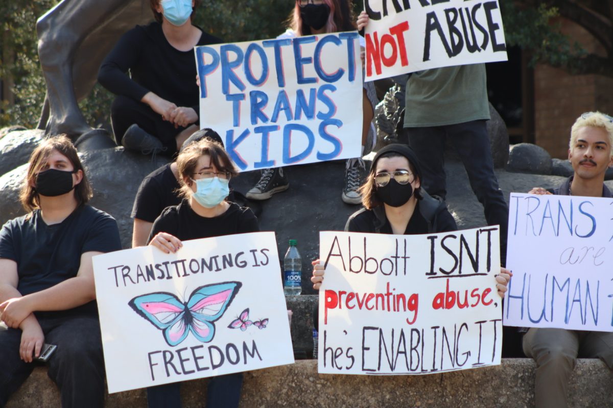 Protestors sit and hold signs at the Stallions during the March for Trans Youth, Wednesday, March 2, 2022, at Texas State. The march was organized in response to Gov. Greg Abbott’s recent order directing state officials to handle gender-affirming treatment to minors as child abuse.
