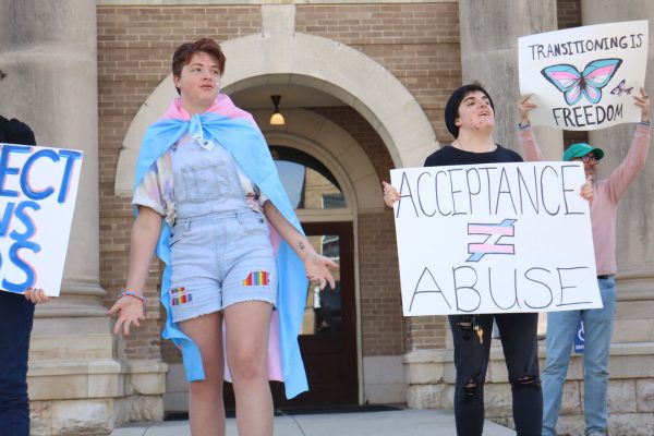 Protestors look at cars passing by during the March for Trans Youth, Wednesday, March 2, 2022, at the Hays County Historic Courthouse. The march was organized in response to Gov. Greg Abbott’s recent order directing state officials to handle gender-affirming treatment to minors as child abuse.