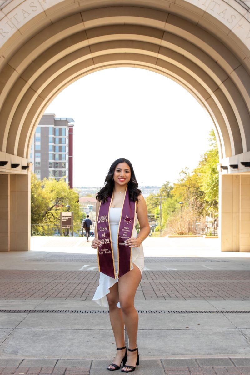 Texas+State+public+relations+senior+Nadia+Gonzales+poses+for+a+graduation+photo+in+front+of+the+UAC+arch%2C+April+1%2C+2022.