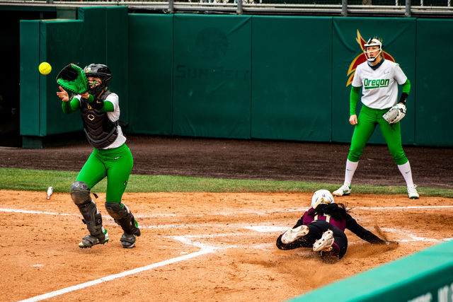 Texas State sophomore utility Anna Jones (14) slides into home base before the Duck catcher can tag her out during the home opener against the University of Oregon, Thursday, Feb. 17, 2022, at Bobcat Softball Stadium. The Bobcats lost 3-7.