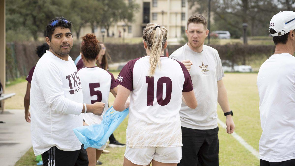 Coaches Nathan Stockie (right) and Henry Zapata (left) talk to Wimberly Wright (middle) as she heads off the field.