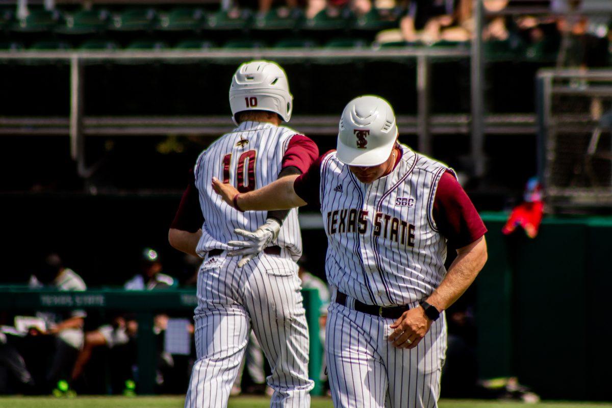 Texas State baseball head coach Steven Trout high fives senior infielder Justin Thompson (10) after he makes a run to home plate during a game against Coastal Carolina, Sunday, March 27, 2022, at Bobcat Ballpark. The Bobcats won the weekend series 2-1.
