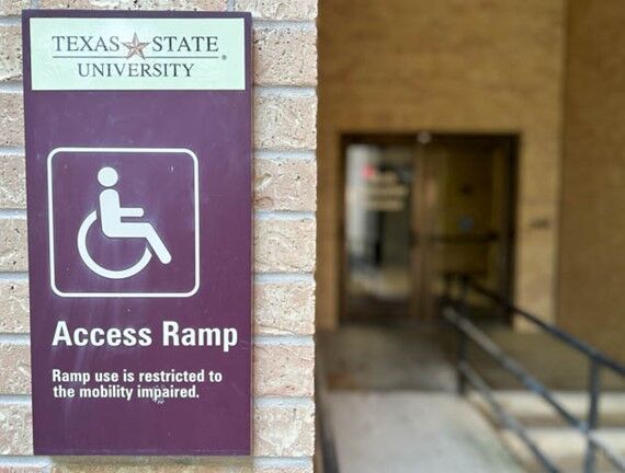 A plaque outside Derrick Hall shows that an access ramp leads to the building.