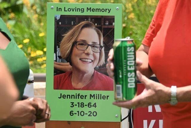 Pamela+Watts+holds+a+24oz+can+of+Dos+Equis+beer+in+front+of+a+memorial+sign+for+Jennifer+Miller+while+talking+to+KXAN+reporter+Jala+Washington%2C+Thursday%2C+June+10%2C+2021%2C+at+San+Marcos+City+Hall.+An+identical+can+was+found+on+the+night+of+the+collision+in+the+car+of+Sgt.+Ryan+Hartman%2C+who+refused+a+blood+alcohol+draw+at+the+scene.