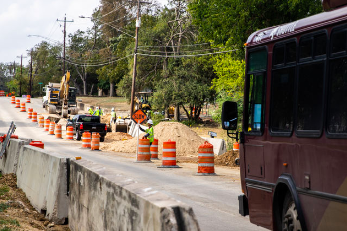 Construction workers conduct traffic while continuing the Sessom-Academy Street project, Monday, Oct. 24, 2022, next to the Bobcat Soccer Complex.