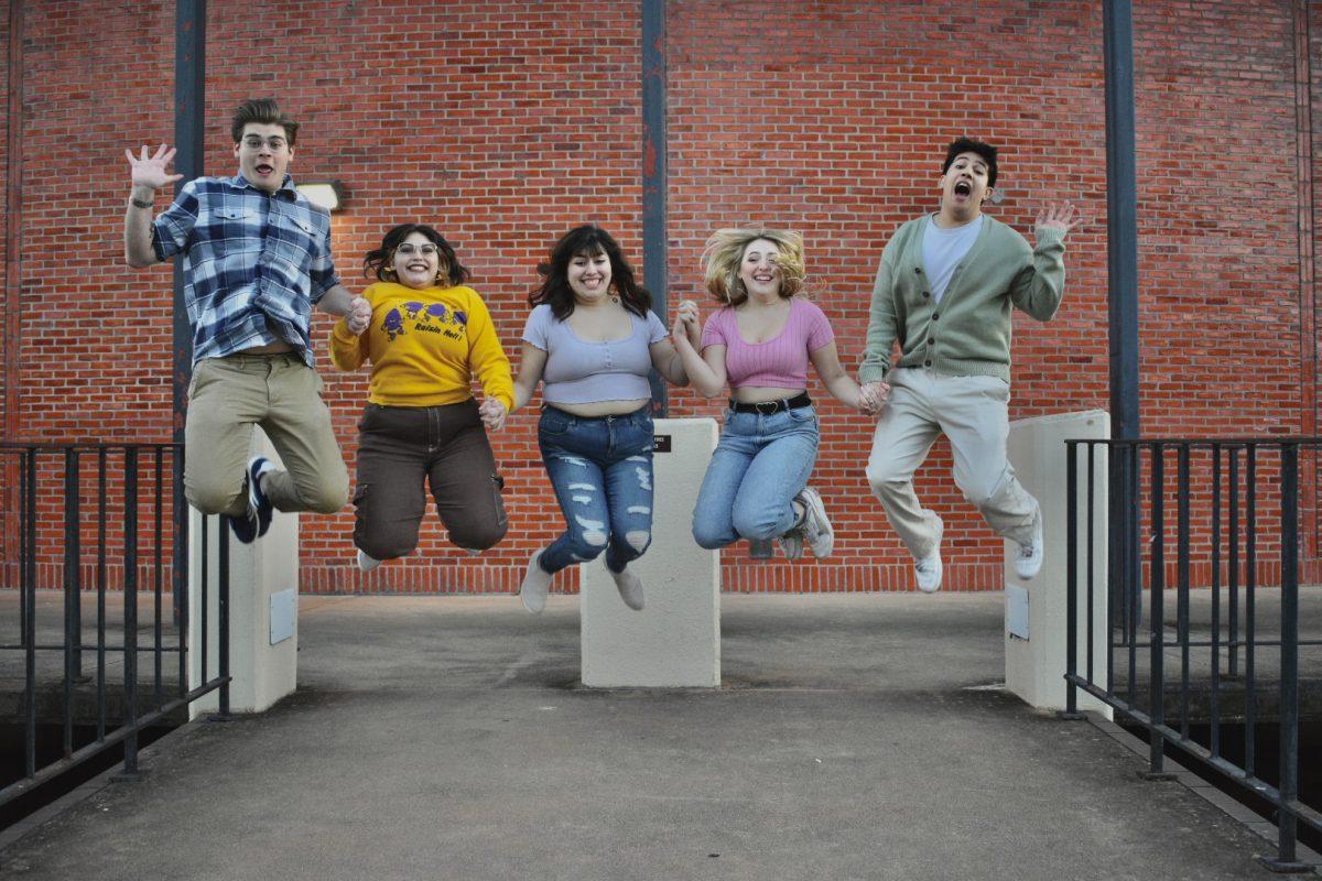 The 2023 Officers of the COSMO Theatre Troupe jump for a photo, Thursday, Jan. 19, 2023, outside of the Theatre Center.