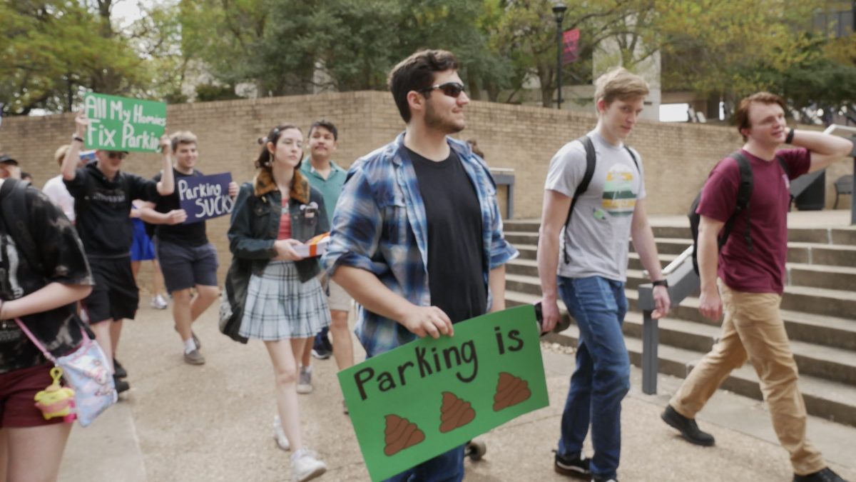 Electrical engineering junior Alexander Johnston (center) marches through the Quad with ParkTXST to deliver petitions to fix parking to the presidents office on Wednesday, March 8, 2023.