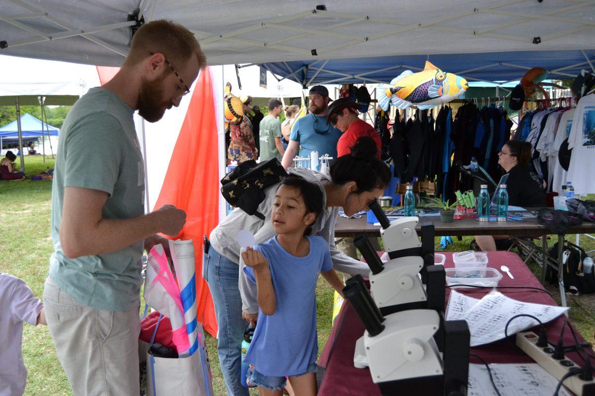 A family views specimens from the San Marcos River through microscopes, Saturday, April 22, 2023, at the 10th Annual Earth Day San Marcos Festival at Spring Lake.